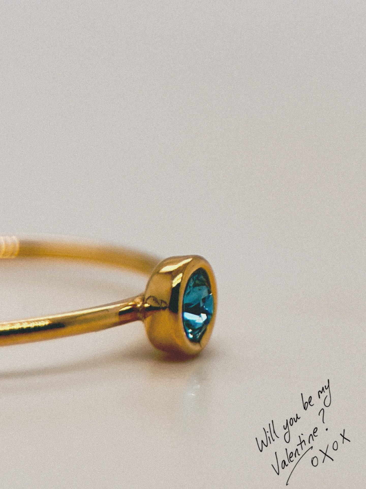 A ring with a blue gem sits on a blank white background.